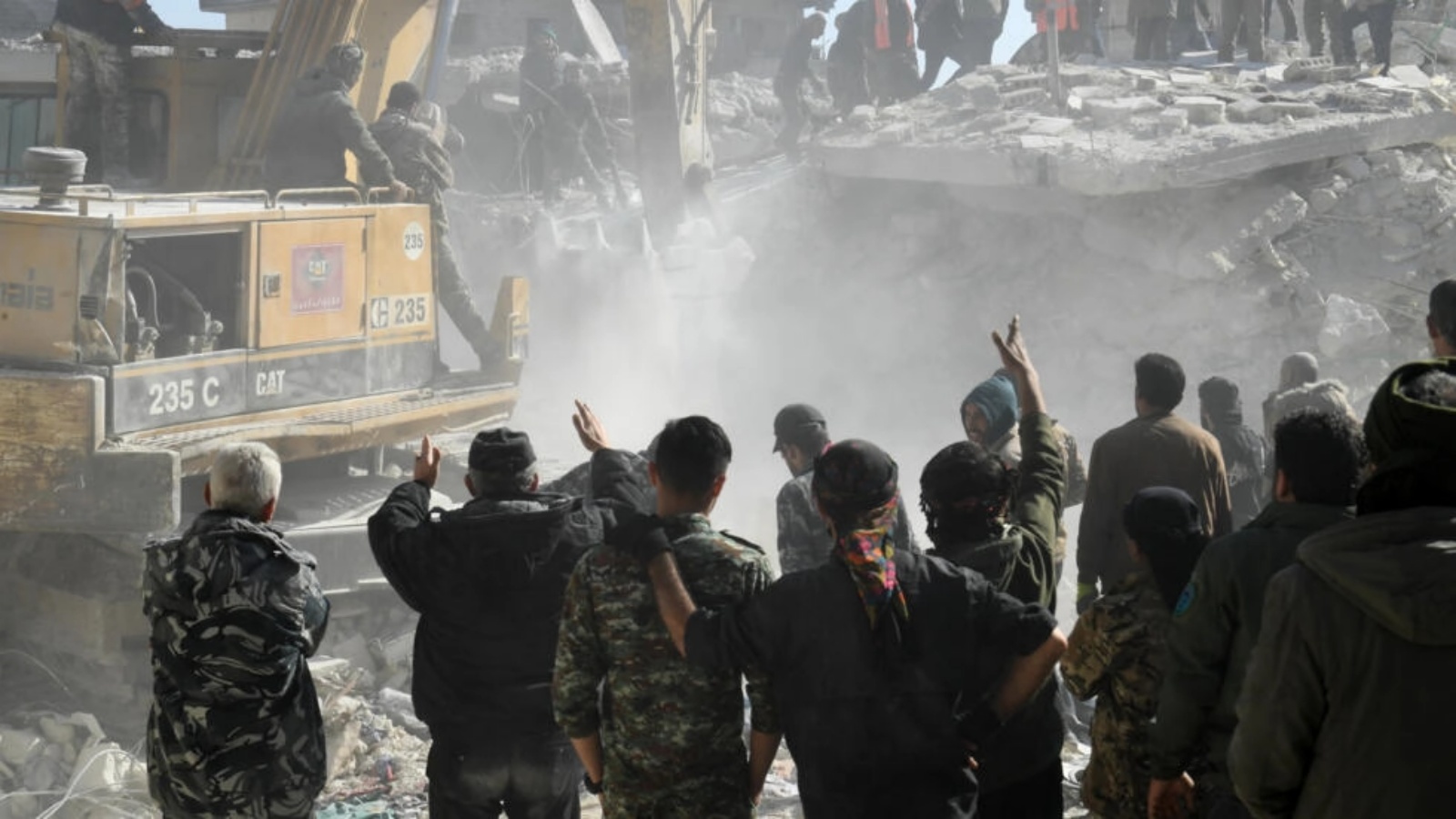 رجال يشاهدون عناصر الإنقاذ يبحثون عن ناجين بعد انهيار مبنى في حلب بشمال سوريا في 22 يناير 2023 