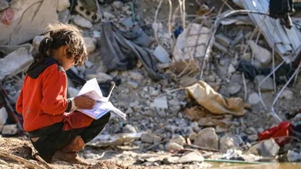 طفلة تجلس على آثار عمارة دمرها الزلزال في عفرين السورية