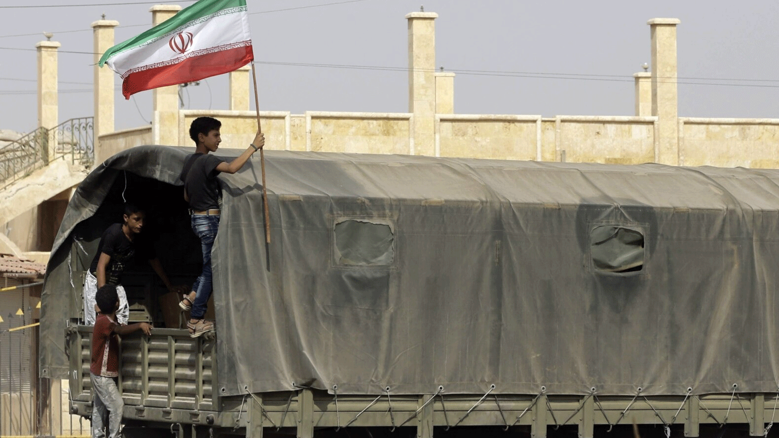 صورة أرشيفية لفتى سوري يحمل العلم الإيراني مع وصول شاحنة قدمتها إيران إلى مدينة دير الزور بشرق البلاد