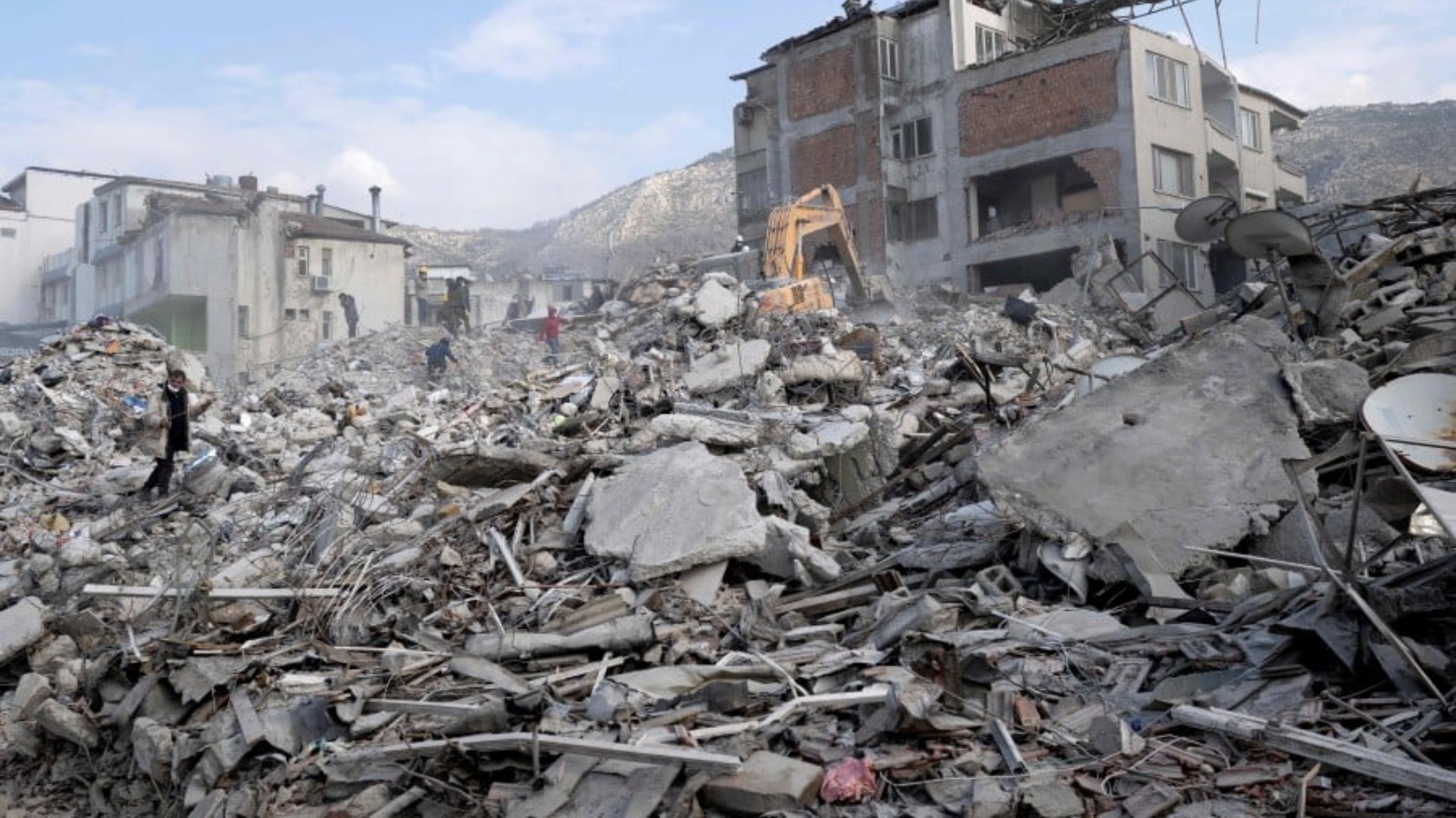 أشخاص يسيرون على مبانٍ مدمرة في مدينة أنطاكيا التاريخية في هاتاي في 11 فبراير 2023.