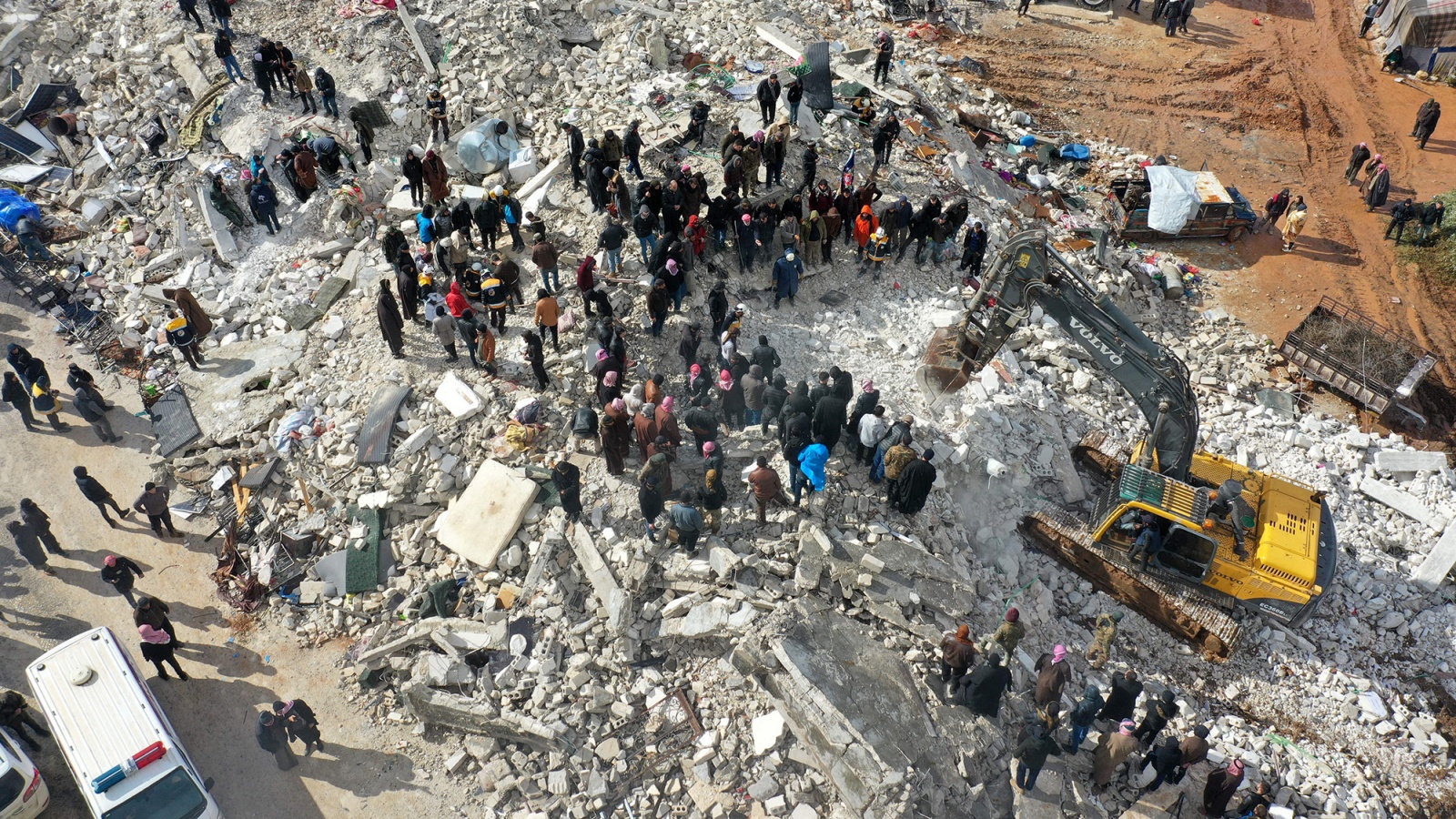 سكان يبحثون عن ضحايا وناجين وسط أنقاض المباني المنهارة إثر زلزال ضرب قرية بسنية بمحافظة إدلب السورية في 6 فبراير.