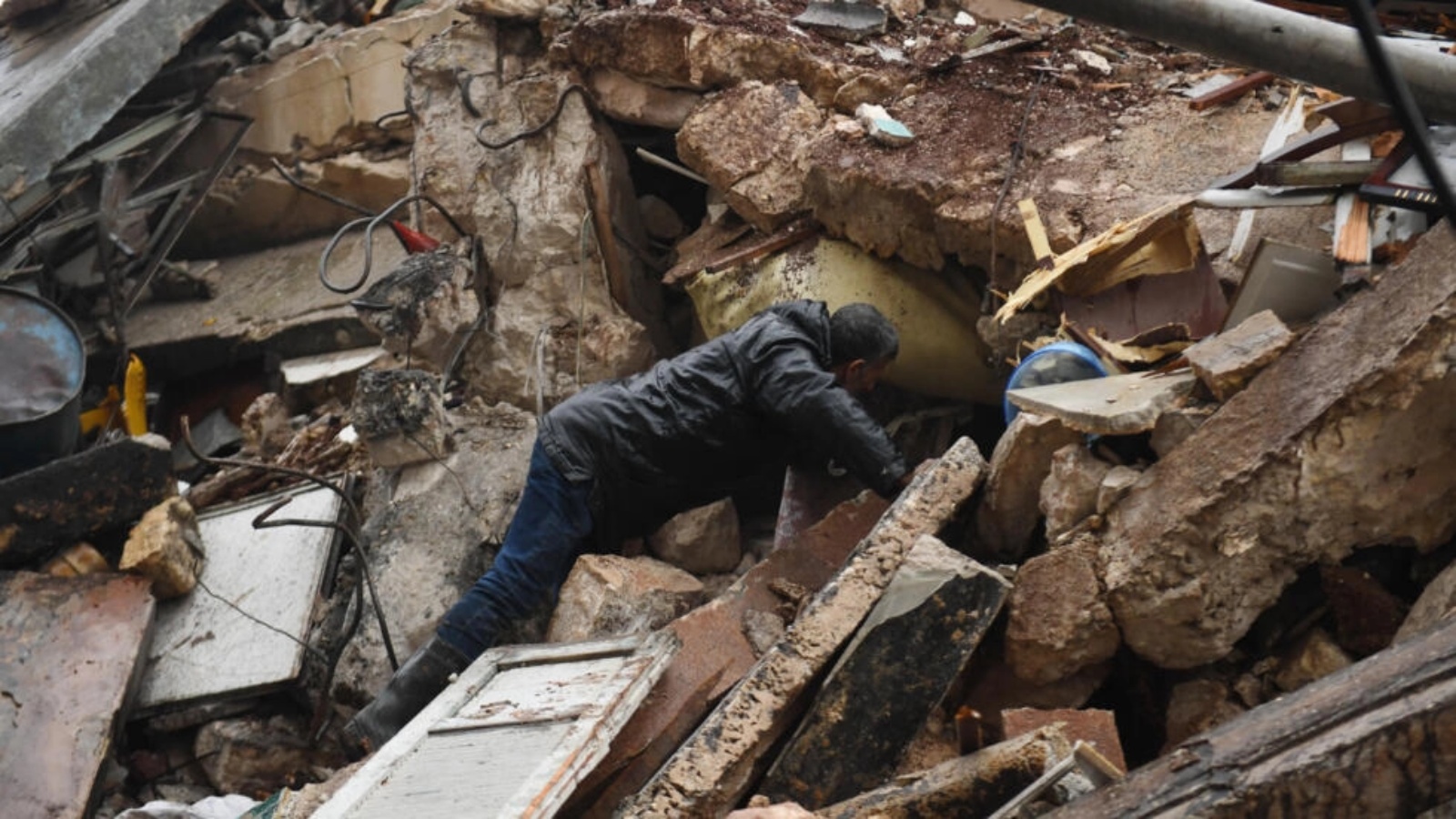 رجل يبحث عن ناجين بين أنقاض مبنى منهار في حلب في منطثة سيطرة النظام السوري بعد زلزال قوته 7,8 درجات ضرب تركيا وسوريا في السادس من فبراير 2023