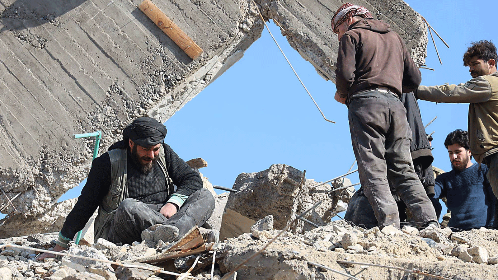 رجلٌ سوري يبكي وهو يجلس فوق أنقاض مبنى منهار في 7 شباط\ فبراير 2023 في بلدة جندريس في الجزء الذي يسيطر عليه المتمردون من محافظة حلب بعد زلزال مميت