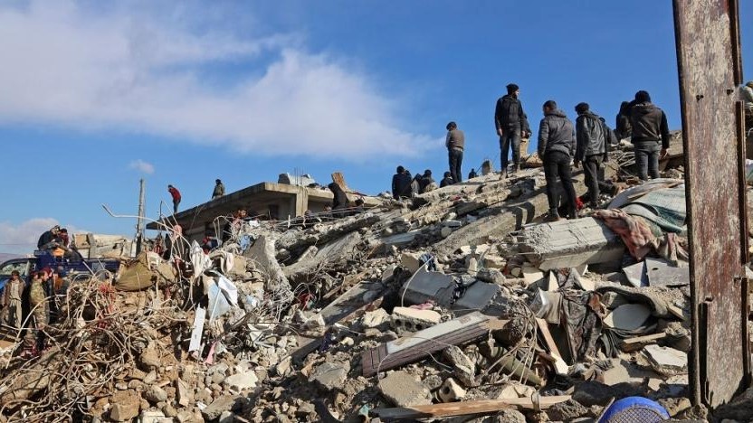 رجال إنقاذ سوريون يتجمعون فوق أنقاض أحد المباني المنهارة ، في 7 شباط 2023 ، في بلدة جندريس في الجزء الذي تسيطر عليه المعارضة من محافظة حلب ، مع استمرار عملية البحث في أعقاب الزلزال المدمر