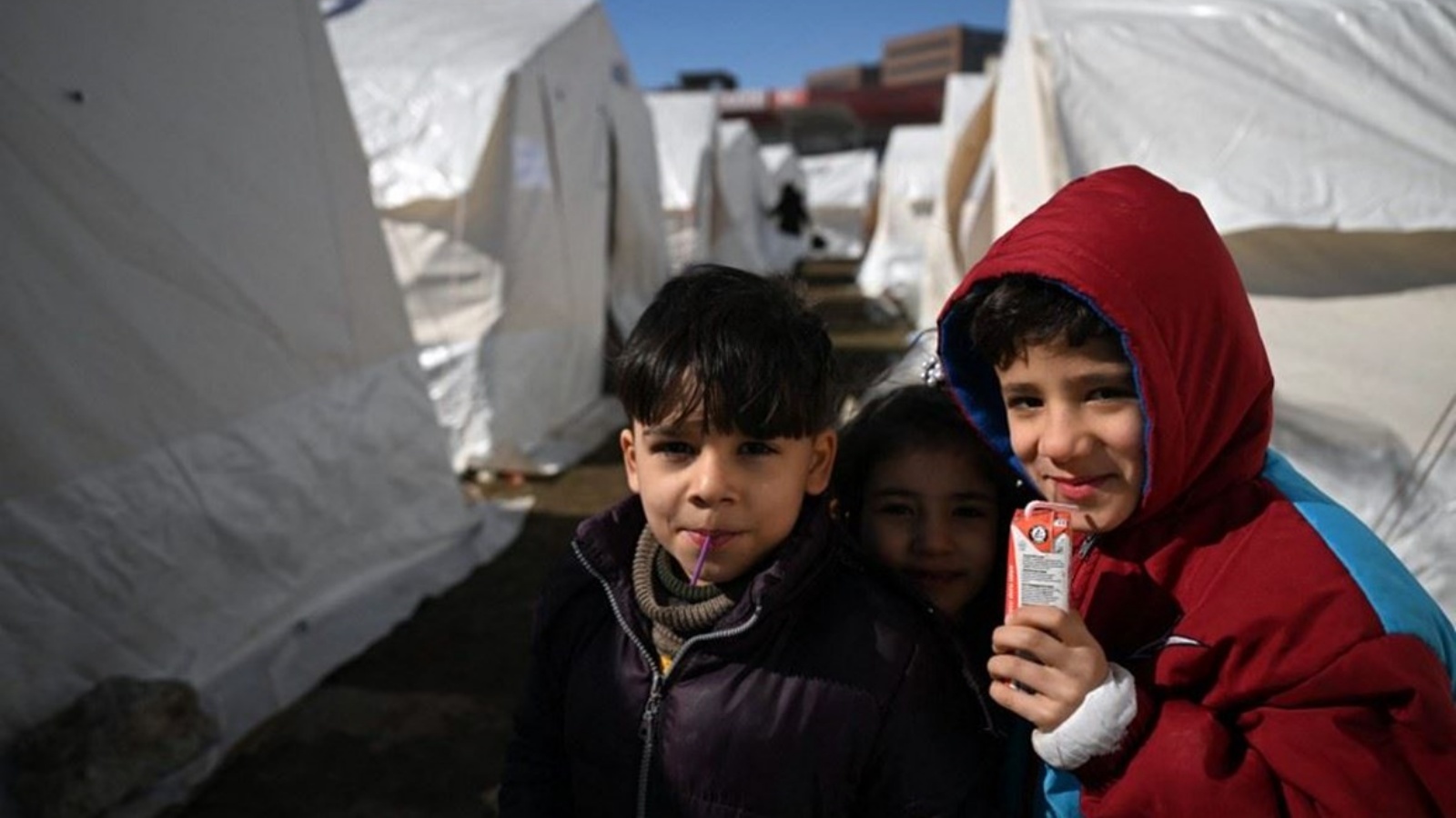 أطفال يقفون بالقرب مخيم أقامته الحكومة في مدينة كهرمان مرعش جنوب شرق تركيا