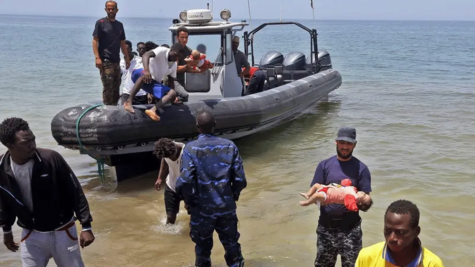 صورة لأفراد من قوات الأمن الليبية يحملون أطفال كمهاجرين نجوا من غرق زورق مطاطي قابل للنفخ قبالة سواحل ليبيا