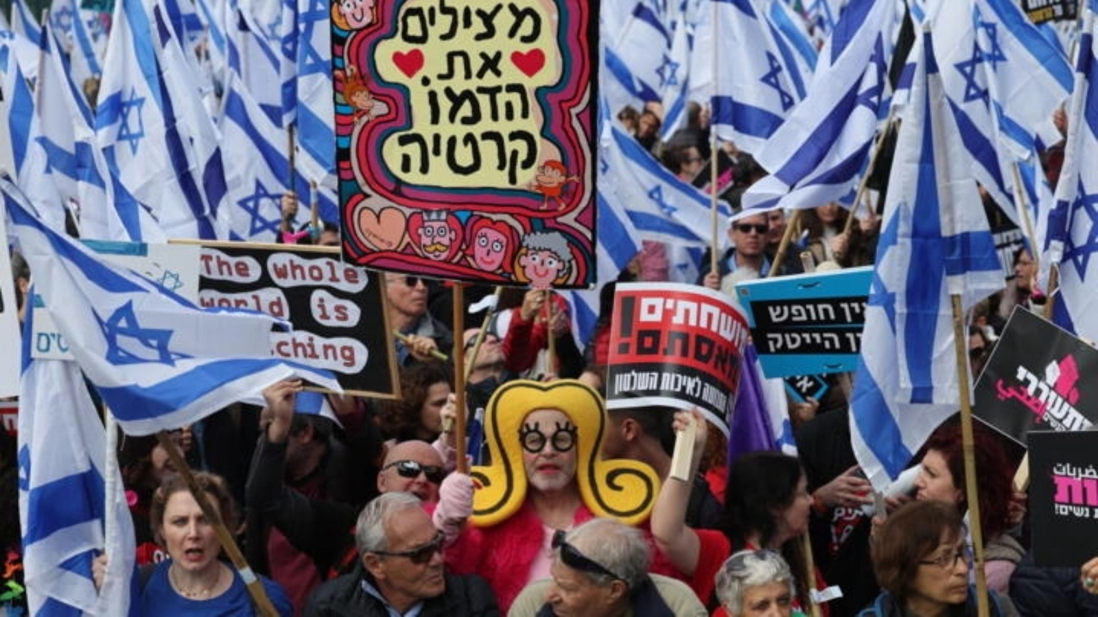متظاهرون إسرائيليون يلوحون بالعلم الإسرائيلي ولافتات خط عليها شعارات ضد مفترحات تعديل النظام القضائي في إسرائيل وذلك أمام البرلمان الإسرائيلي (الكنيست) في 13 فبراير 2023