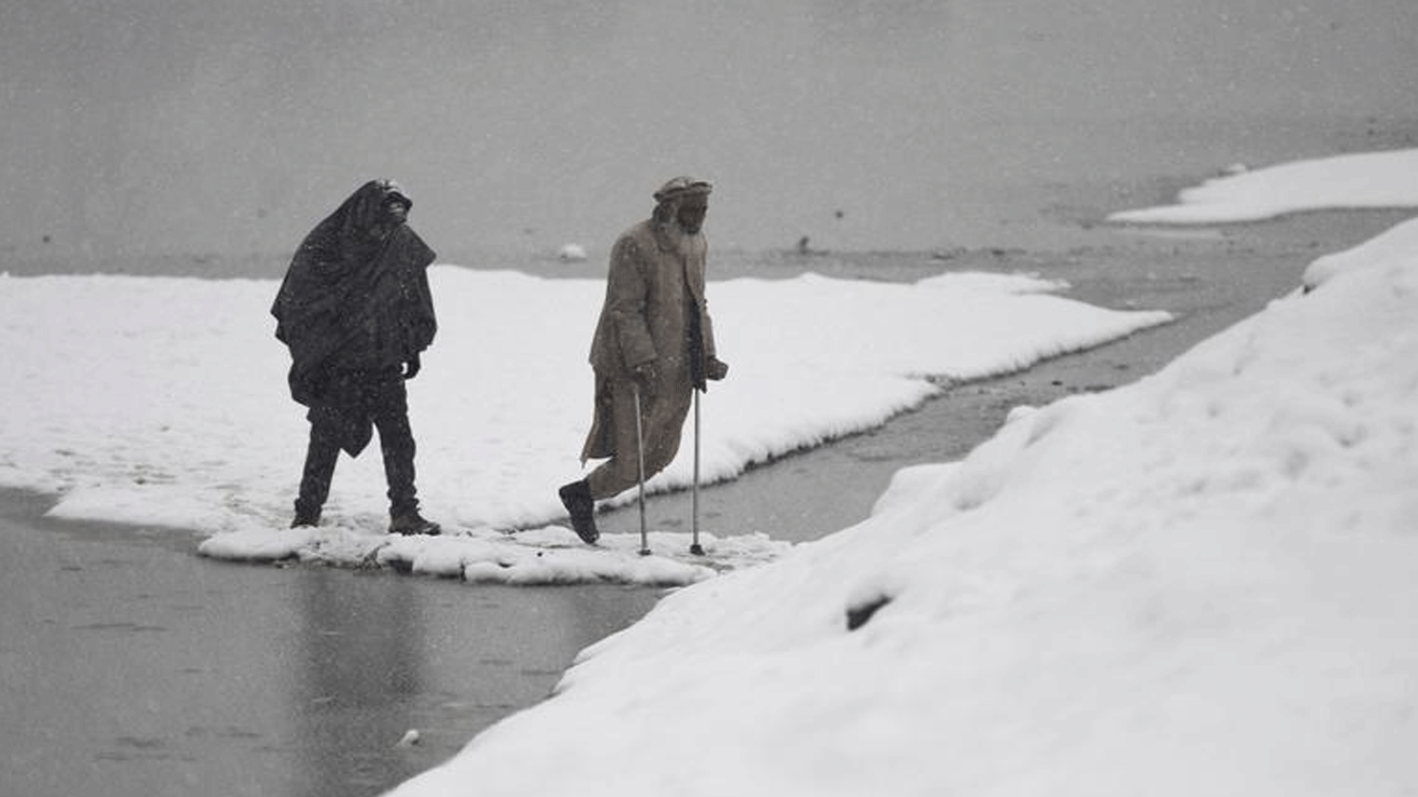 رجال يسيرون على طول طريق أثناء تساقط الثلوج في بحيرة الشهداء في كابول في 9 فبراير 2023. قُتل ثلاثة أشخاص بينهم طفل وأصيب اثنان آخران عندما ضرب انهيار جليدي قرية في مقاطعة بدخشان شمال أفغانستان في 14 شباط\ فبراير 2023