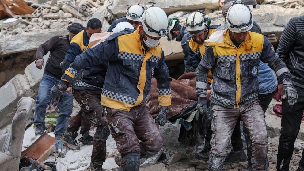 عناصر من الدفاع المدني السوري المعروف باسم الخوذ البيضاء ينقلون مصابين من أنقاض المباني في قرية عزمارين ، سوريا، في 7 فبراير 2023