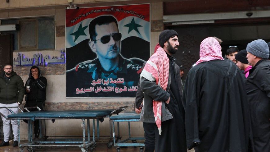 سوريون يتجمعون قرب ملصق لرئيس النظام السوري بشار الأسد خارج قسم الطوارئ في مستشفى بعد الزلزال المميت، حماة، سوريا، في 6 فبراير 2023