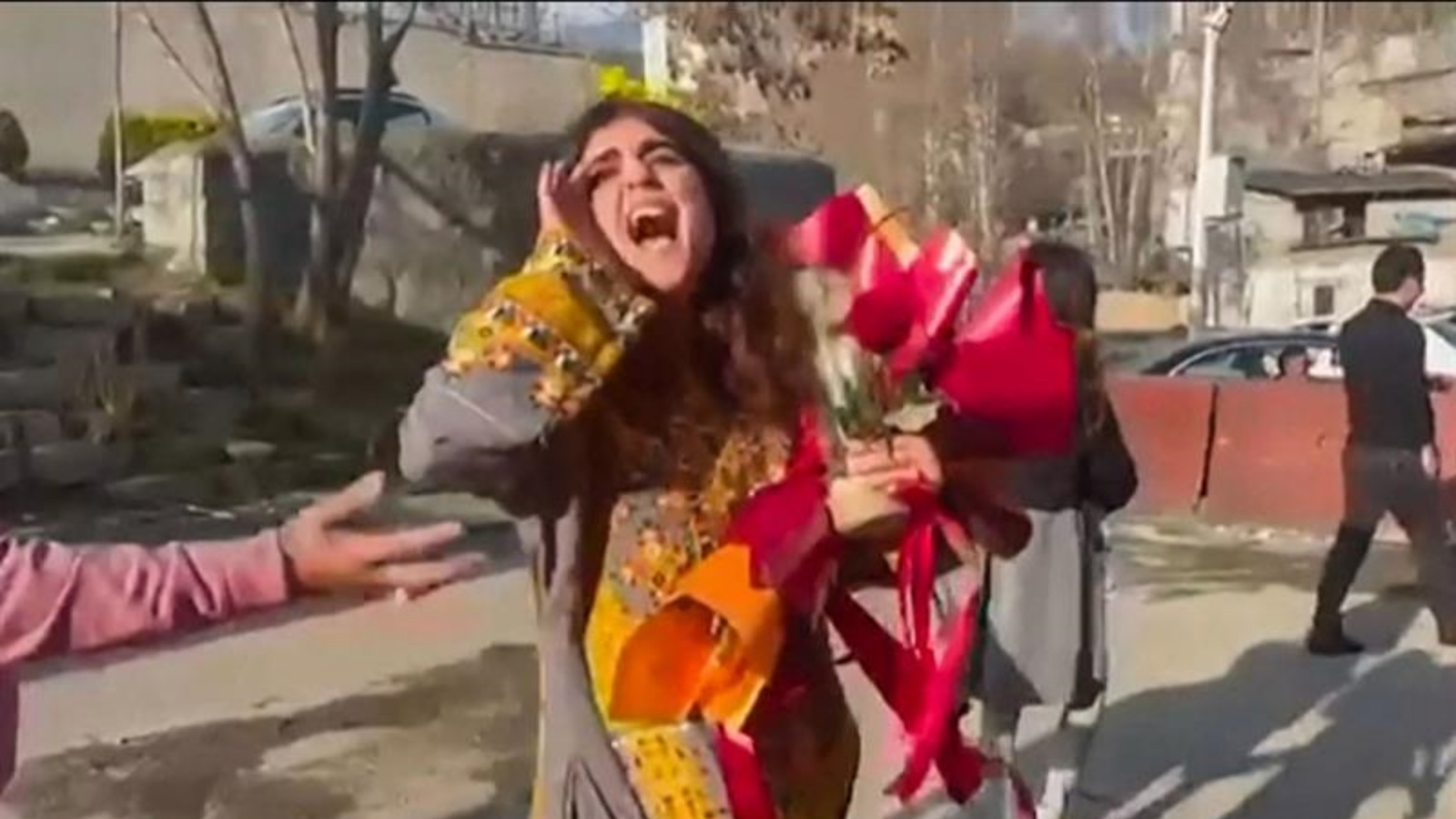 الناشطة والصحفية الإيرانية سبيده جوليان تمشي مع باقة من الزهور خارج جدران سجن إيفين في طهران، بعد إطلاق سراحها، 15 مارس 2023