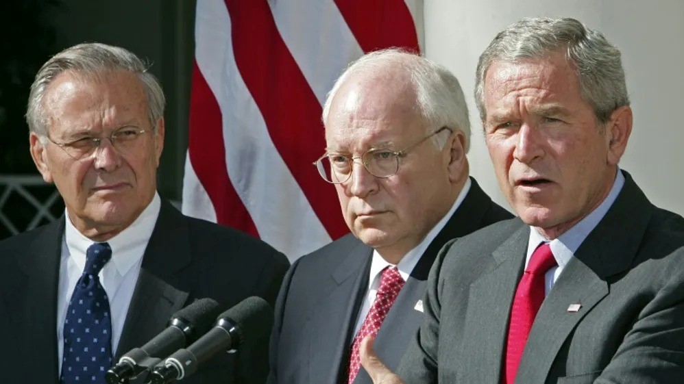 الرئيس الأميركي جورج دبليو بوش، نائب الرئيس ديك تشيني (وسط)، وزير الدفاع دونالد رامسفيلد (يسار)، خلال خطاب ألقاه بوش في 28 سبتمبر 2005، في البيت الأبيض