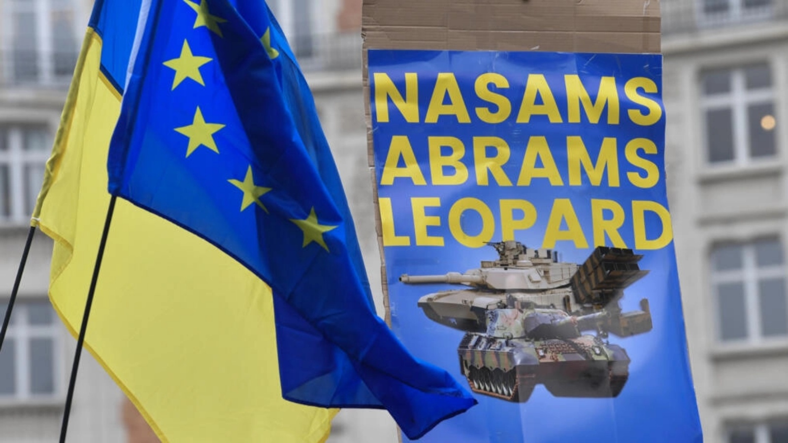 علم أوكراني ولافتة تطالب بتسليح أوكرانيا، خلال مظاهرة دعم أمام مقر الاتحاد الأوروبي في بروكسل في 23 يناير 2023