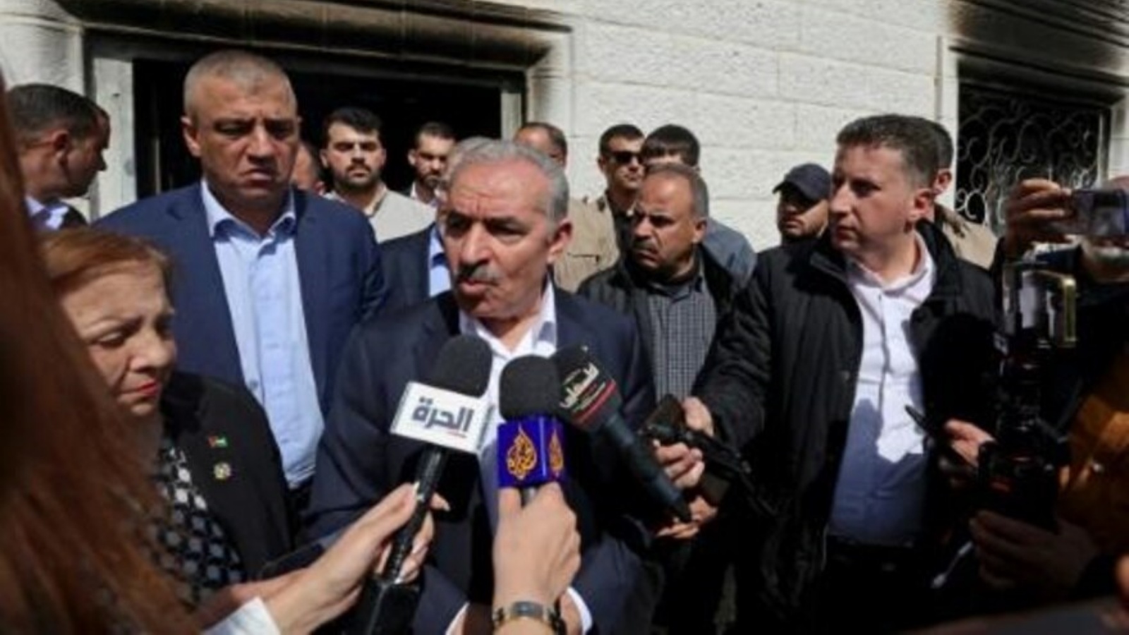 رئيس الوزراء الفلسطيني محمد اشتية (وسط) يتحدث للصحافيين خلال زيارة تفقدية لبلدة حوارة في شمال الضفة الغربية في الأول من مارس 2023