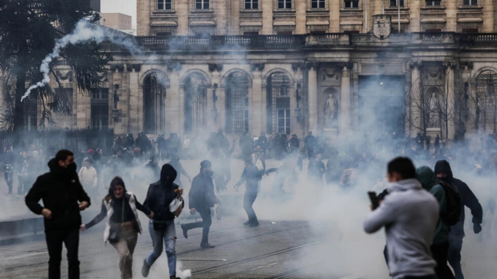 متظاهرون يهربون من قنابل الغاز المسيل للدموع أمام بلدية مدينة بوردو الفرنسية خلال احتجاجات على إصلاح نظام التقاعد، 18 مارس 2023