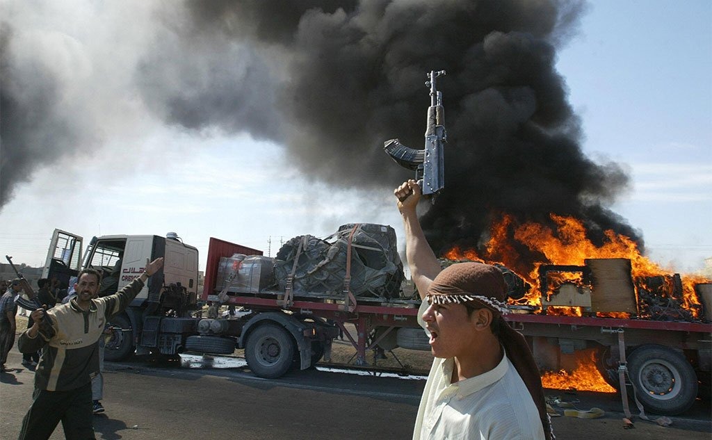 Getty Images مسلحون سنة عراقيون أمام قافلة عسكرية أمريكية محترقة بضواحي الفلوجة عام 2004
