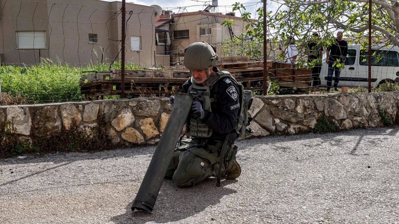 عضو في وحدة ابطال مفعول القنابل بالشرطة الاسرائيلية يتفقد بقايا قذيفة اطلقت من لبنان واعترضتها اسرائيل في بلدة فسوطة الشمالية الخميس