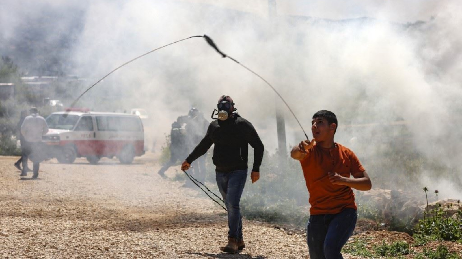 فلسطيني يقذف الحجارة باتجاه جنود إسرائيليين خلال مواجهات معهم اثر احتجاج على إقامة بؤر استيطانية إسرائيلية، في بيت دجن شرق مدينة نابلس بالضفة الغربية المحتلة 14 أبريل 2023