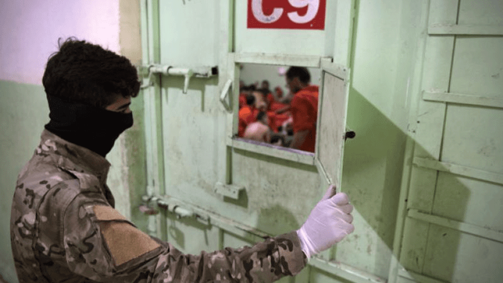 لقطة لجندي يتفقد سجناء داعش داخل أحد سجون قسد في شمال شرقي سوريا