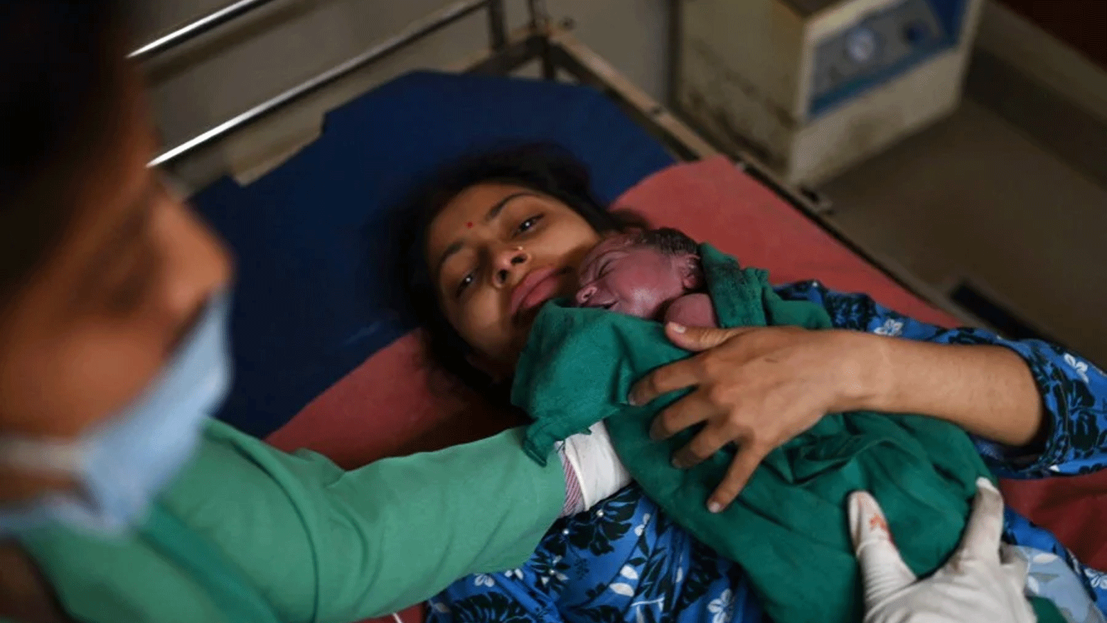 مانو بالا تحتضن طفلتها بعد ولادتها في مستشفى ديهرا المدني بمنطقة كانجرا في هيماشال براديش، في اليوم التاريخي الذي أعلنت فيها الأمم المتحدة تفوق الهند على الصين بعدد السكان