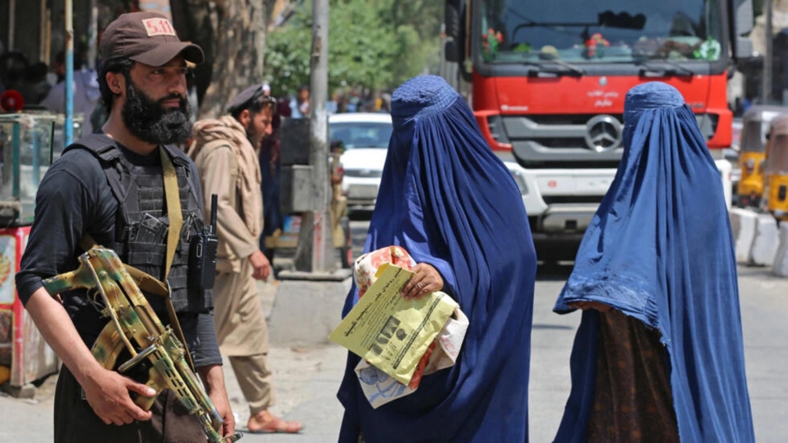 امرأتان أفغانيتان ترتديان البرقع تمران قرب عنصر أمن من حركة طالبان في جلال آباد في أفغانستان في 30 أبريل 2023 