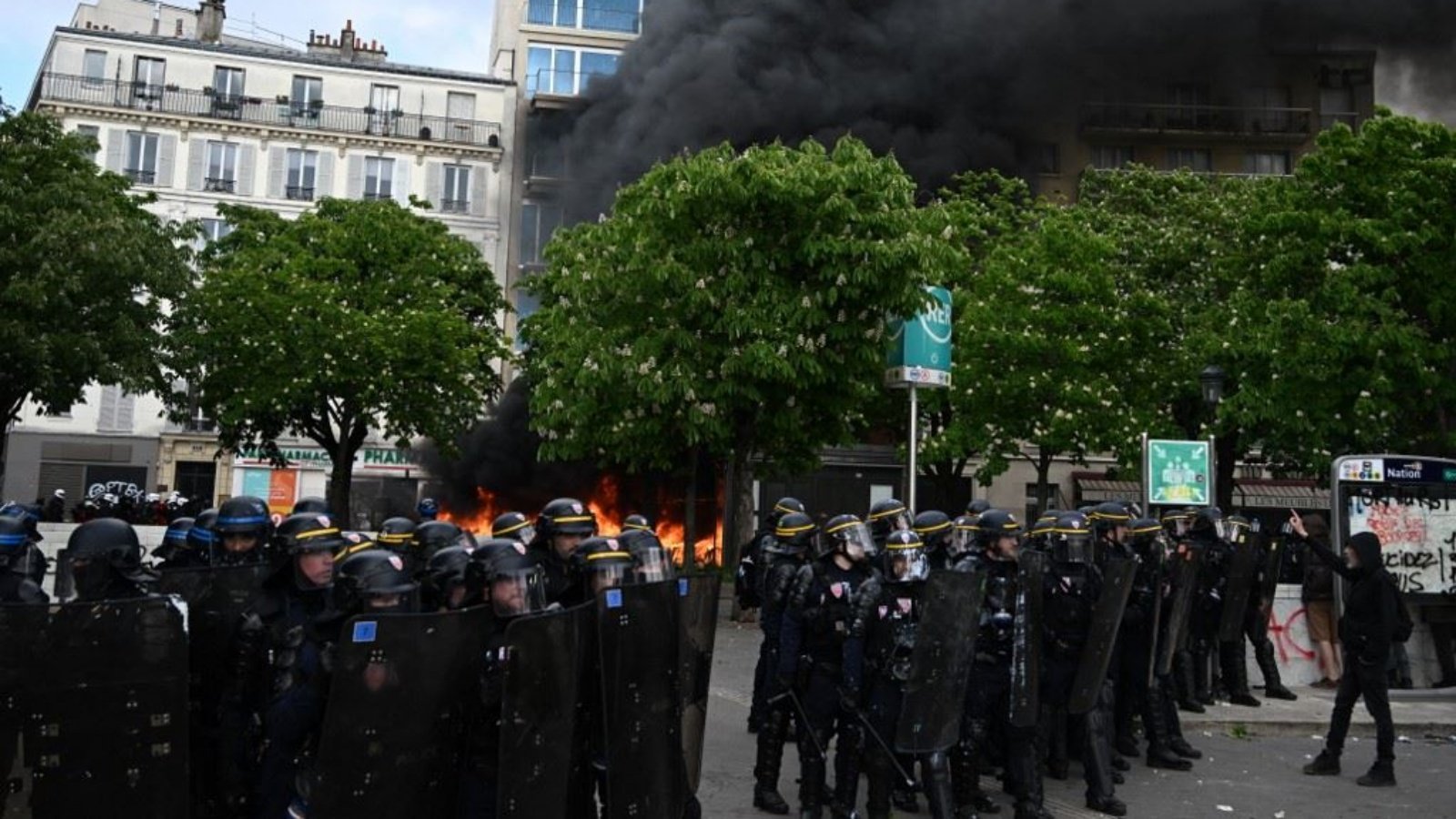 ضباط الشرطة الفرنسية يقفون أمام النار خلال مظاهرة في عيد العمال