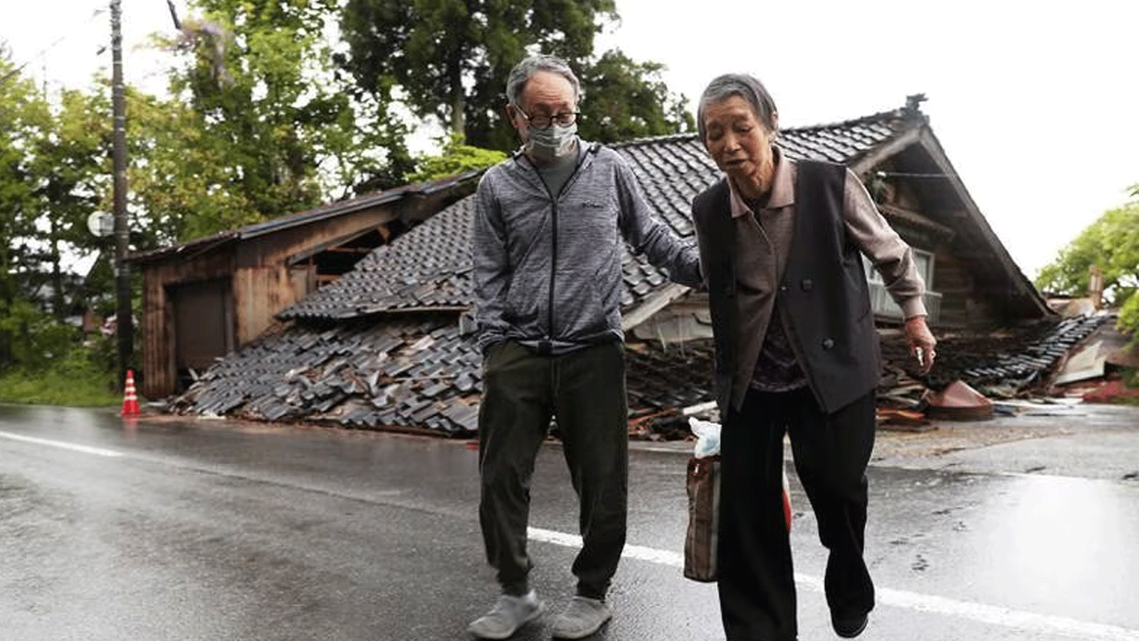 سكان في مدينة سوزو يمرون بجانب منزل انهار عندما ضرب زلزال بقوة 6. 5 درجات محافظة إيشيكاوا اليابانية