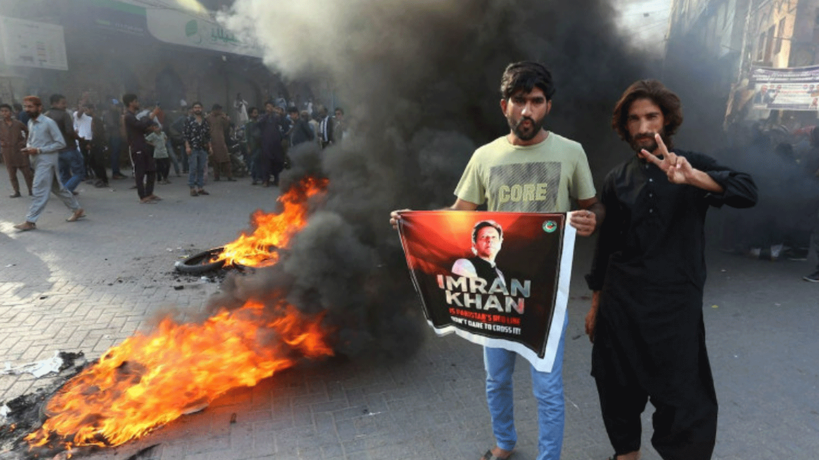 أنصار رئيس الوزراء السابق عمران يقفون بجانب الإطارات المحترقة أثناء قيامهم بقطع طريق خلال احتجاج على اعتقاله. في حيدر أباد يوم الثلاثاء. 9 أيار\مايو 2023