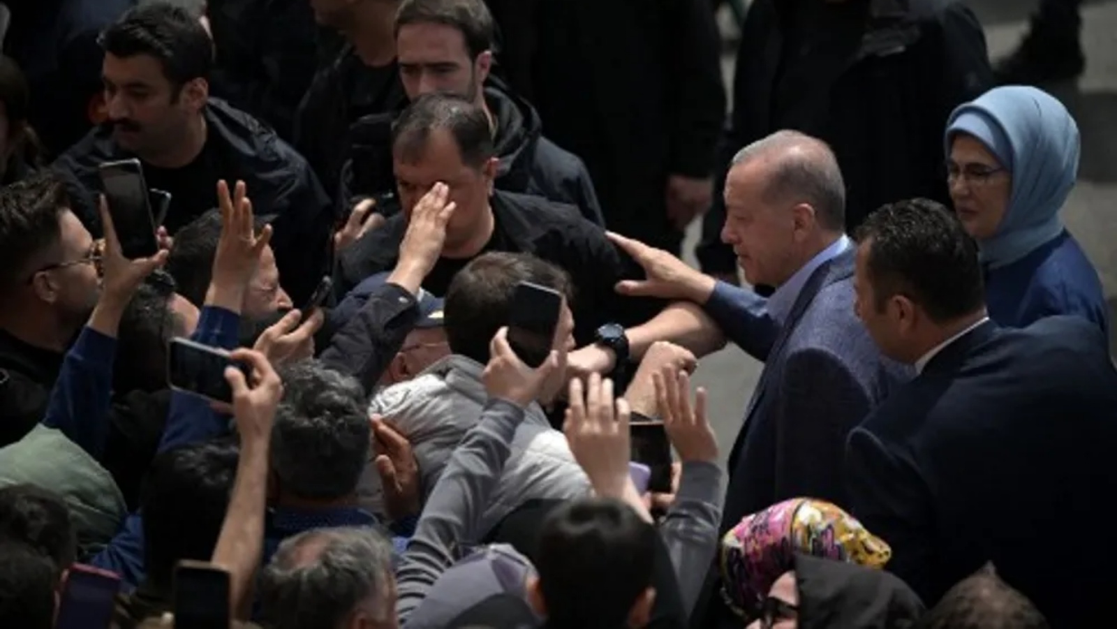 الرئيس التركي رجب طيب أردوغان وزوجته أمينة أردوغان (يمين) محاطان بالحشود أثناء مغادرتهم مركز الاقتراع بعد التصويت في الانتخابات الرئاسية والبرلمانية، في اسطنبول، تركيا، في 14 مايو 2023.