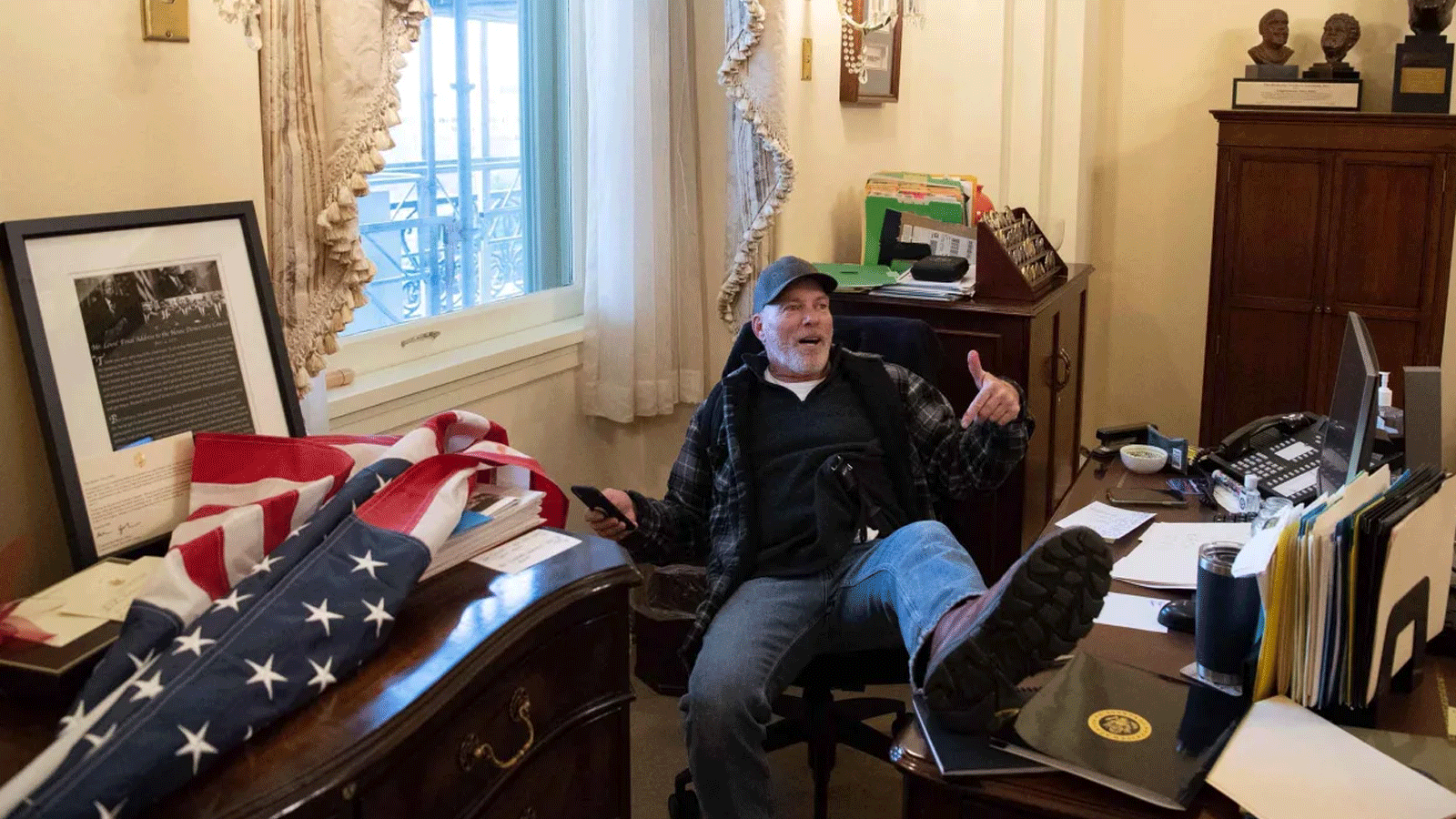 ريتشارد بارنيت، من أنصار الرئيس الأميركي السابق دونالد ترامب، يجلس داخل مكتب رئيسة مجلس النواب الأميركي نانسي بيلوسي(رئيسة مجلس النواب آنذاك) في 6 كانون الثاني\ يناير 2021