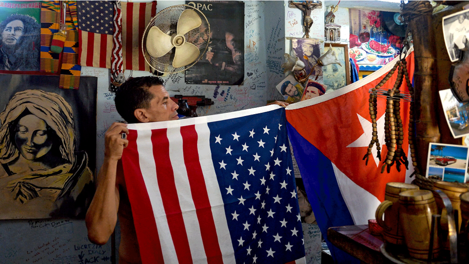 رجل يعرض علمي الولايات المتحدة وكوبا في منزله في هافانا
