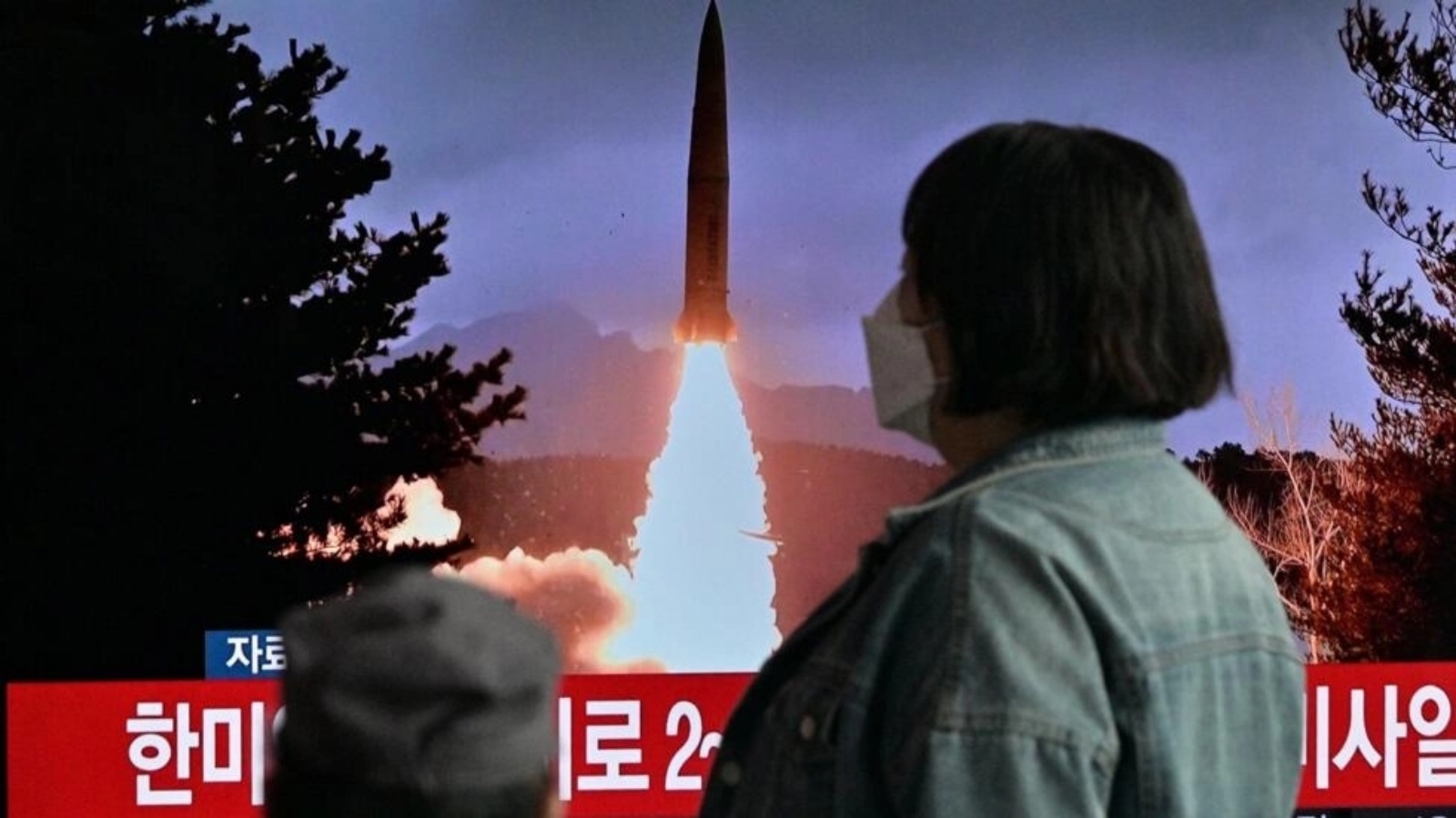 امرأة تمر أمام بث تلفزيوني يظهر مشاهد من تجربة صاروخية كورية شمالية، في محطة قطارات في سيول في 19 مارس 2023 