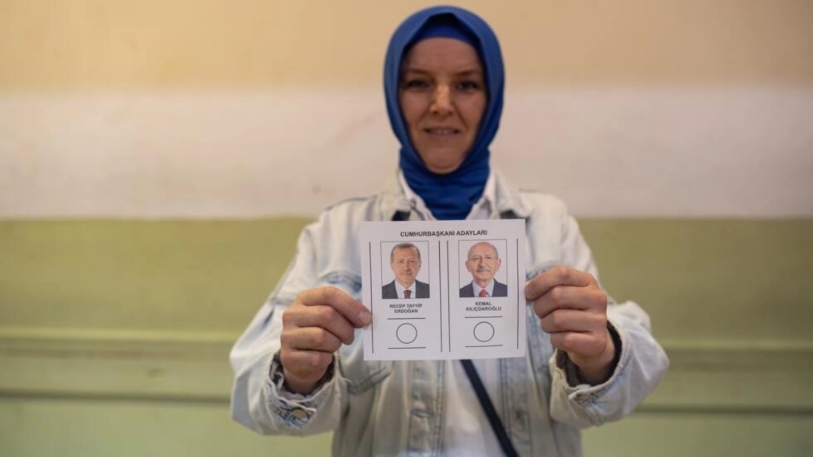 امرأة تحمل بطاقة اقتراع تظهر المرشحين للانتخابات الرئاسية التركية رجب طيب إردوغان (يمين) وكمال كيليتشدار اوغلو في مركز اقتراع في محافظة قوجه ايلي في 28 مايو 2023