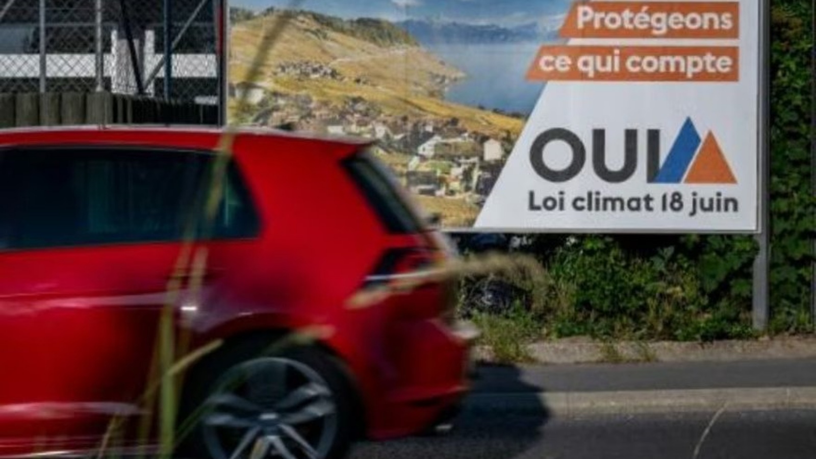 سيارة تمر من أمام لافتة انتخابية مؤيدة لمشروع قانون المناخ في لوزان بتاريخ 14 يونيو 2023