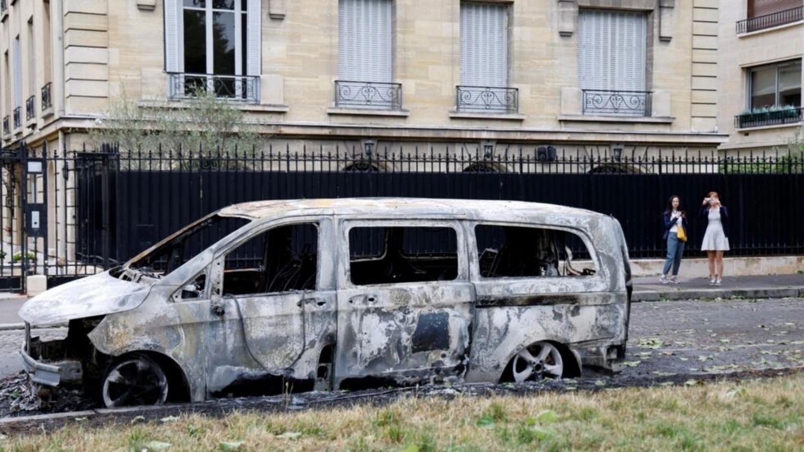 مارة يلتقطون صوراً لمركبة احترقت في الدائرة السادسة من باريس، في الأول من تموز/يوليو 2023 مع تواصل أعمال الشغب جراء مقتل مراهق برصاص الشرطة في نانتير في ضاحية العاصمة الفرنسية في 27 يونيو