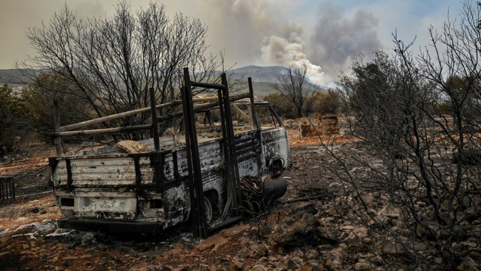 سيارة محترقة بينما تصاعد دخان من غابة مشتعلة في مستوطنة أوي بونتيوي بالقرب من أثينا 19 يوليو 2023