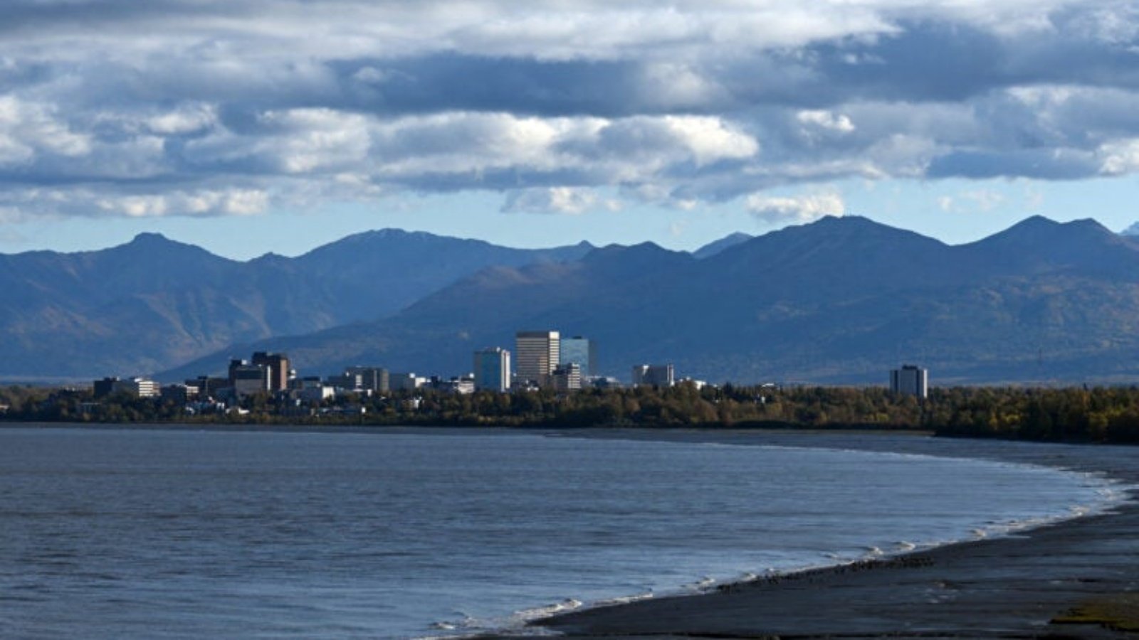 غيوم متلبدة فوق جبال Chugach ووسط مدينة أنشوراج كما تُرى من عبر مياه Knik Arm في Earthquake Park في أنشوراج، ألاسكا في 17 سبتمبر 2022