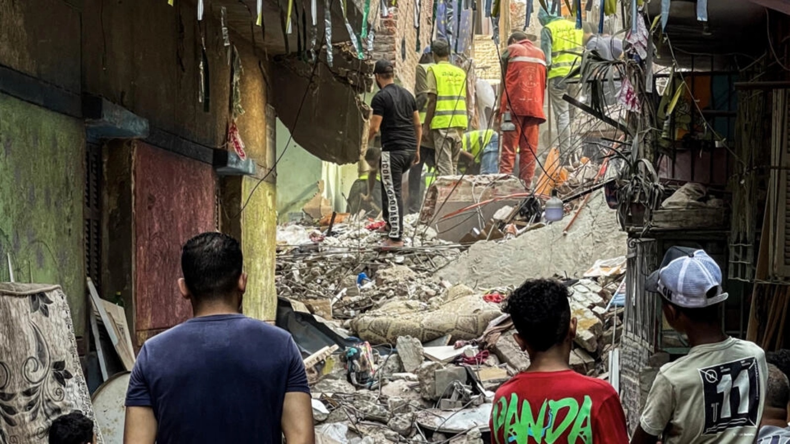 شبان يراقبون محاولة البحث عن ناجين من انهيار مبنى بمنطقة حدائق القبة في القاهرة في 17 يوليو 2023