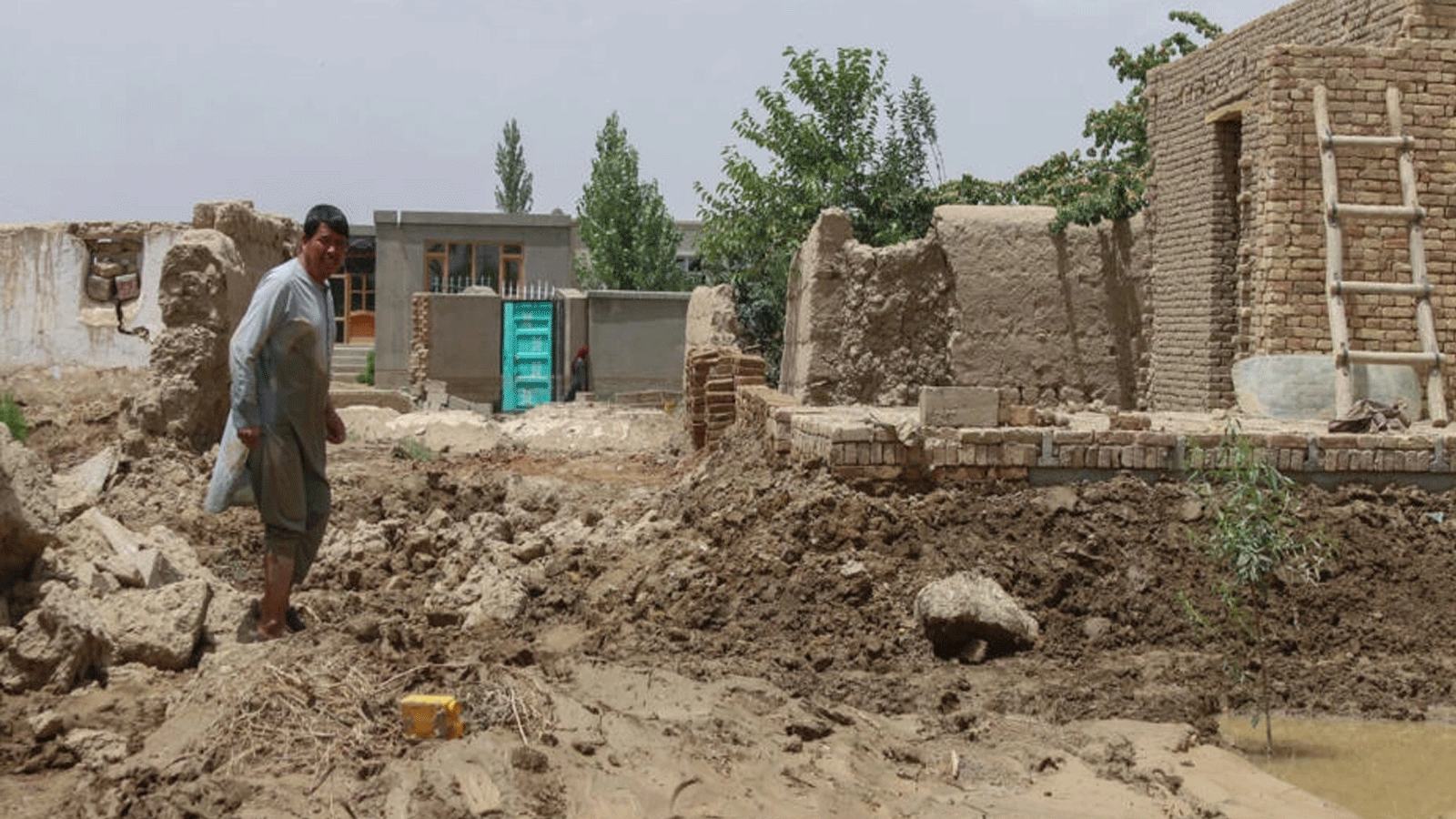 مواطنون يسيرون في الوحول إثر فيضانات مفاجئة تسببت بها أمطار غزيرة في منطقة خير آباد في ولاية غزنة بوسط أفغانستان في 23 تموز/يوليو 2023