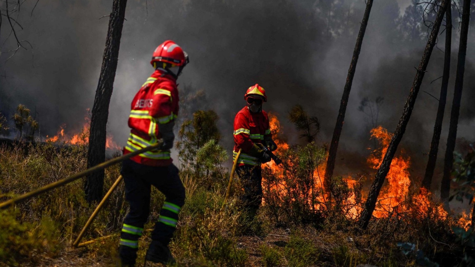 عنصرا إطفاء يحاولان إخماد الحريق الذي اندلع وسط البرتغال