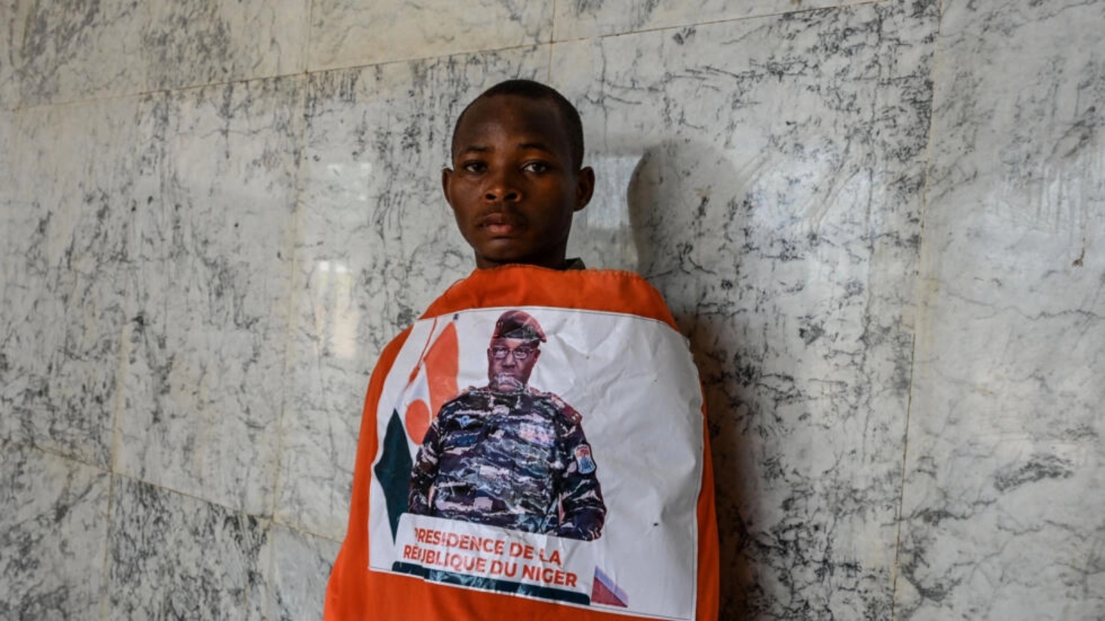 شاب يلف نفسه بعلم للنيجر تتوسطه صورة قائد الانقلاب الجنرال عبد الرحمن تياني في إستاد في نيامي في 13 أغسطس 2023