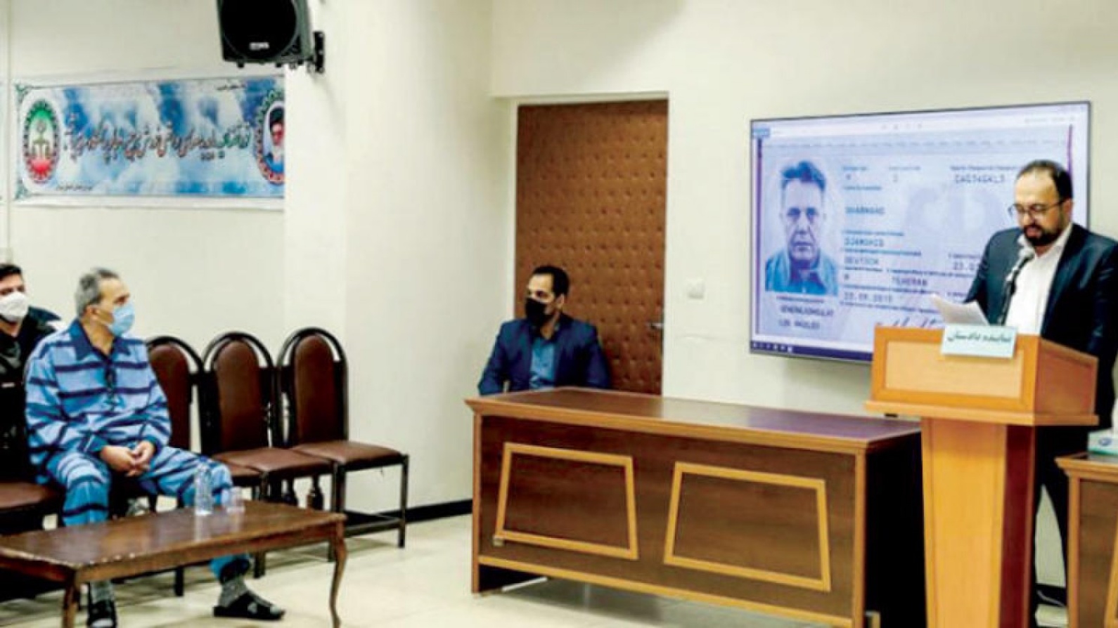 جمشيد شارمهد بينما يعرض جواز سفره الألماني على شاشة أثناء المحاكمة في فبراير 2022