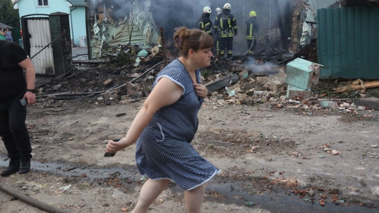 امرأة تمر بجوار رجال إطفاء خلال مكافحتهم النيران في منزل تضرر بعد هجوم صاروخي على قرية خارج كييف 30 أغسطس 2023