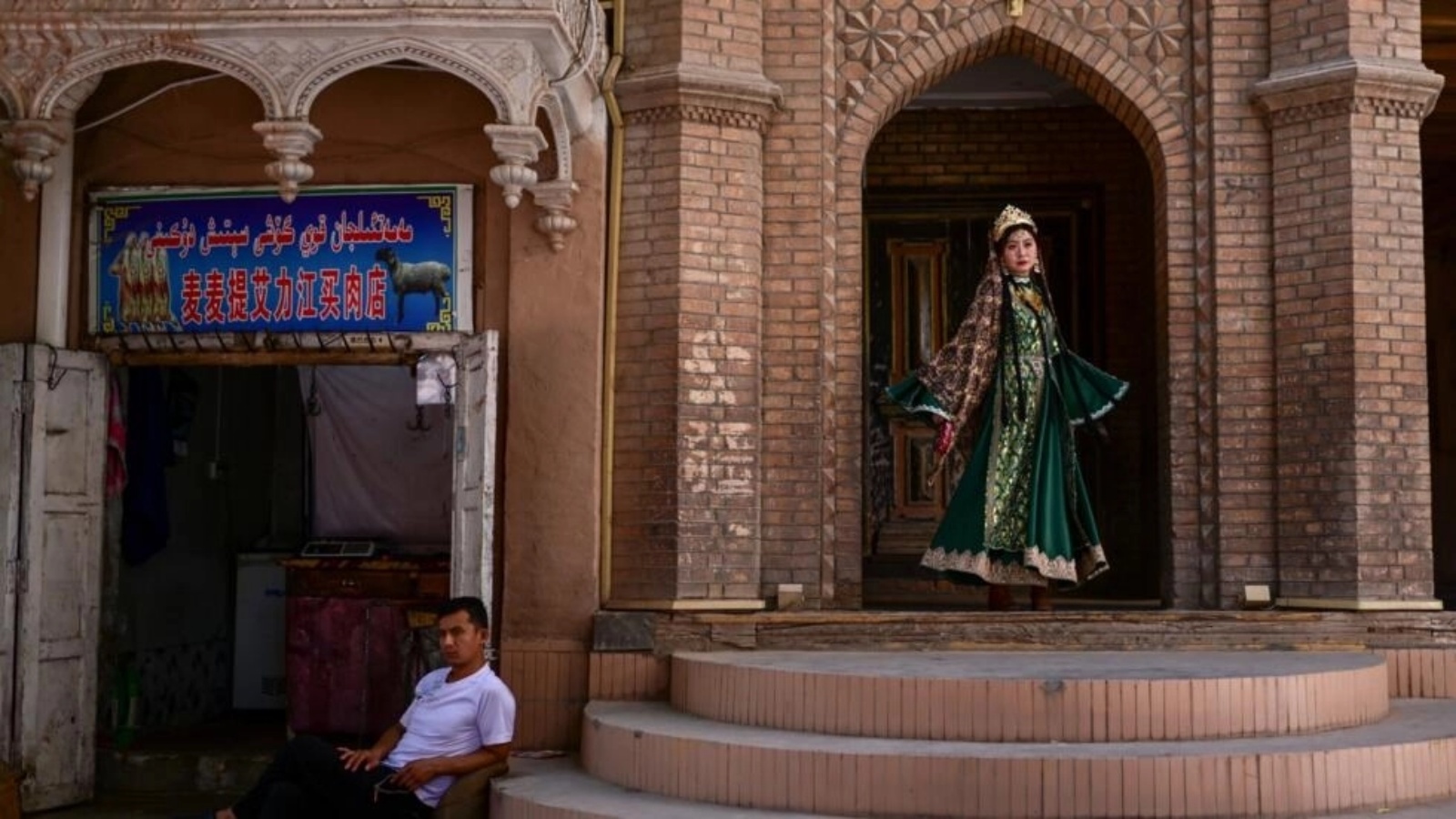 سيدة ترتدي زي الأويغور التقليدي تلتقط صورة في منطقة كشقار السياحية في شينجيانغ 
