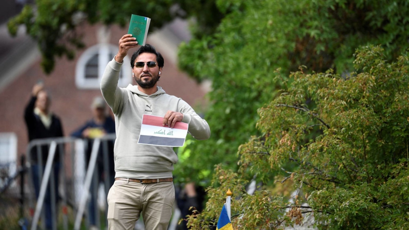 اللاجئ العراقي سلوان موميكا يحمل نسخة من المصحف الشريف خلال احتجاج أمام السفارة العراقية في استوكهولم 20 يوليو 2023 
