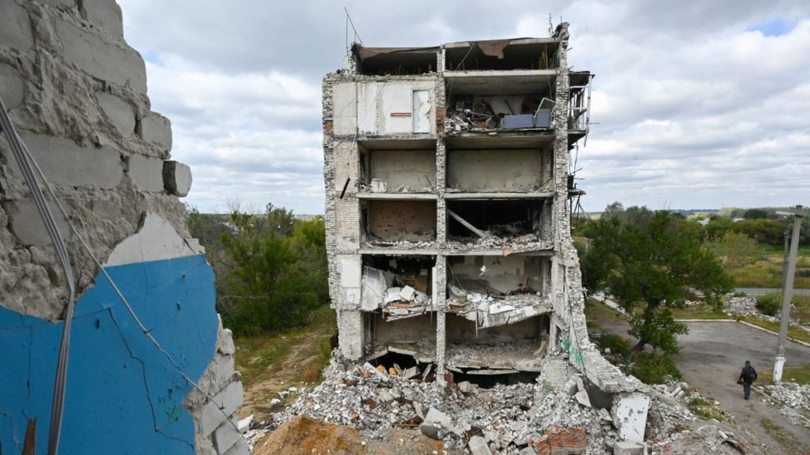 شخص يمر بجوار مبنى سكني مدمر في بلدة إيزيوم بمنطقة خاركيف 10 سبتمبر 2023