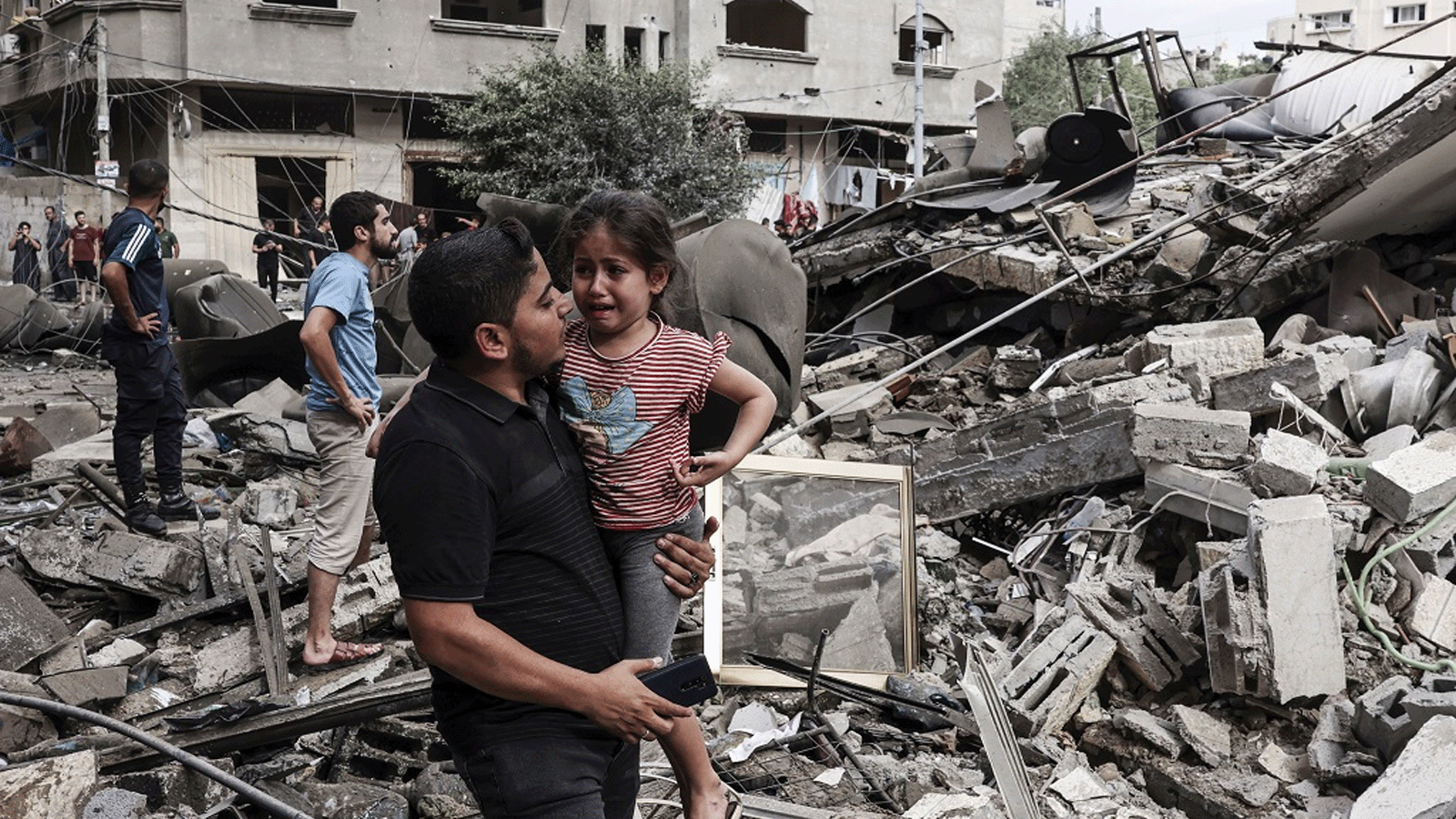 شابٌ ينقل طفلة عقب قصف طائرات الاحتلال لمباني سكنية في غزة