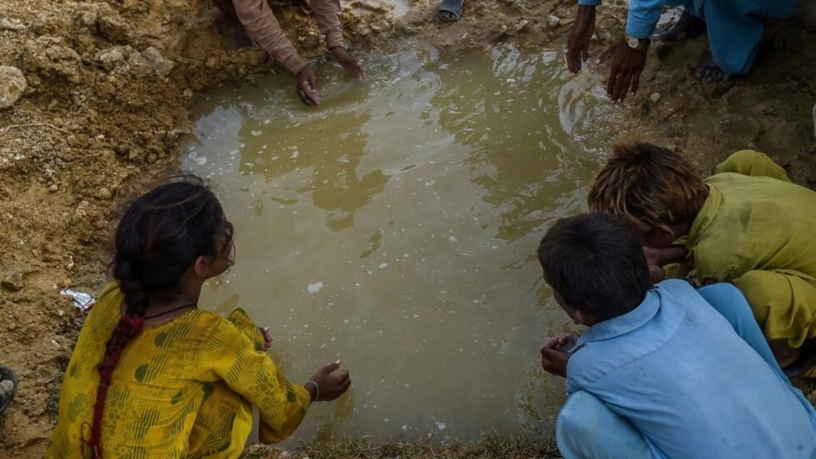 أطفال نزحوا بسبب الفيضانات يشربون من بركة خارج مخيم مؤقت في باكستان. 26 سبتمبر 2022 
