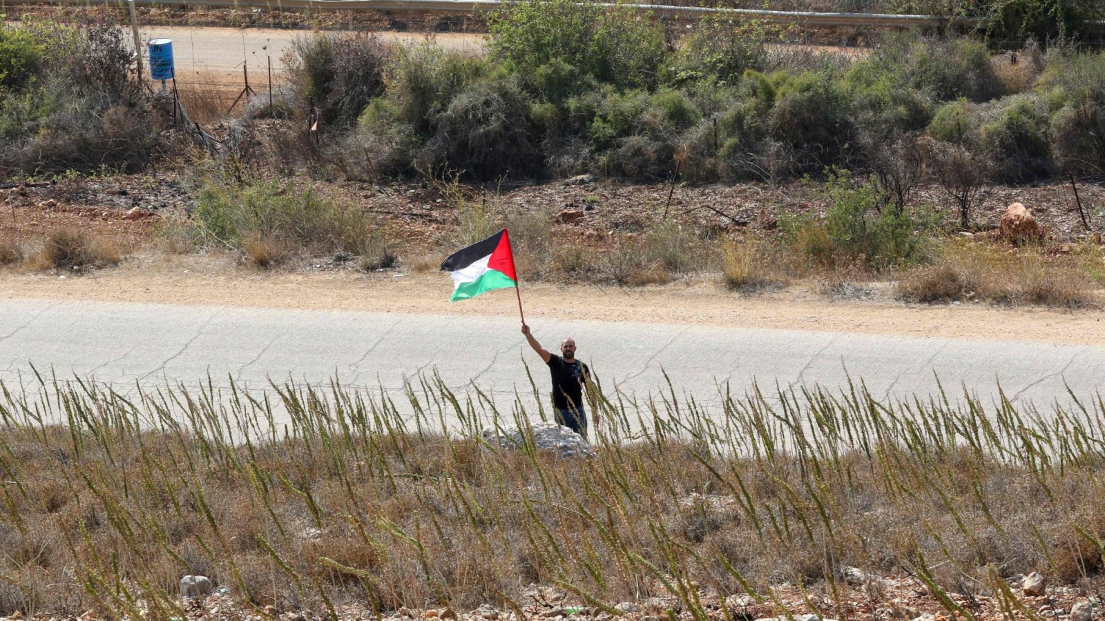 لبناني يلوح بعلم فلسطين في سهل الخيام قرب حدود إسرائيل
