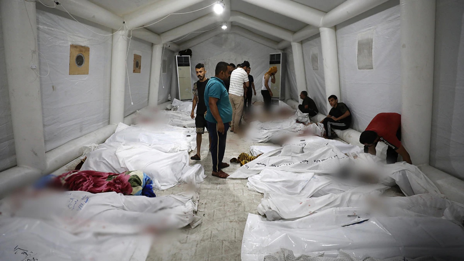 أشخاص بين جثث الفلسطينيين الذين قتلوا بعد انفجار في المستشفى الأهلي العربي وسط قطاع غزة